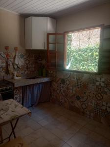 a kitchen with a window and a tile wall at Casa Centro pertinho da praia in Piúma