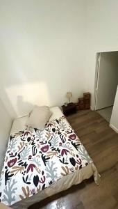 a bedroom with a bed with a floral comforter at Le plein centre in Montbrison