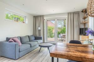 een woonkamer met een bank en een tafel bij Hello Zeeland - Vakantiehuis Duinenburg 22A in Domburg