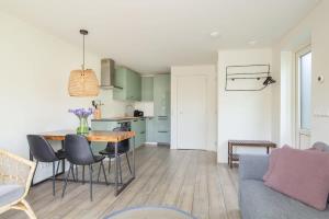 een keuken en woonkamer met een tafel en stoelen bij Hello Zeeland - Vakantiehuis Duinenburg 22A in Domburg