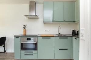 een keuken met witte kasten en een spoelbak bij Hello Zeeland - Vakantiehuis Duinenburg 22A in Domburg