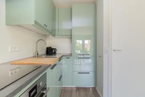 een keuken met witte kasten en een houten aanrechtblad bij Hello Zeeland - Vakantiehuis Duinenburg 22A in Domburg