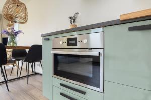 een keuken met een oven in een blauwe kast bij Hello Zeeland - Vakantiehuis Duinenburg 22A in Domburg +13 foto's