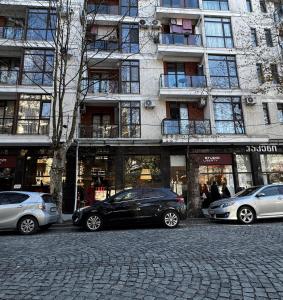 un gruppo di auto parcheggiate davanti a un edificio di White Bridge Riverside a Kutaisi