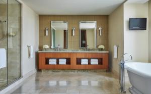 a bathroom with a tub, sink and mirror at Four Seasons St. Louis in Saint Louis
