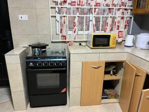 a small kitchen with a stove and a microwave at Cindy's Garden Gate in Accra