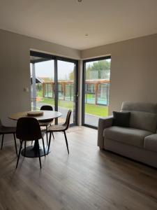 a living room with a couch and a table and chairs at studio Avec piscine et Spa Privatif Extérieur 4 personnes in Lestrem