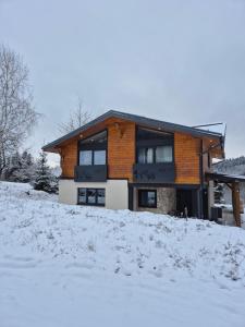 a house on a snow covered hill with at Chata pod Vysokou in Jakubany