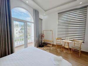 a bedroom with a bed and a table and a large window at Mai House Da Lat in Xuan An
