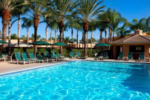 a swimming pool with chairs and palm trees at Sheraton Park Hotel at the Anaheim Resort in Anaheim