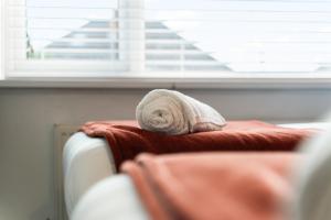 a towel is sitting on top of a bed at Stylish 3 Bedroom Contractor Stay House in Birmingham B23 near M6 & Fort Dunlop with Free Parking and WiFi in Birmingham