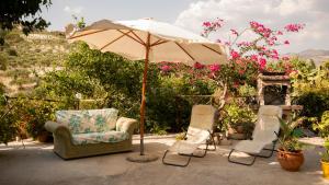 Eine Gruppe Stühle und ein Sonnenschirm auf einer Terrasse in der Unterkunft Case Troccoli in Caltabellotta