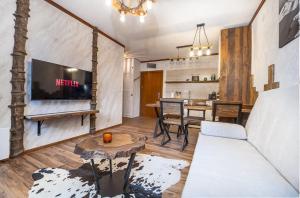 een woonkamer met een bank en een tv bij Host2U Authentic Bansko Apartment - Free Parking in Bansko