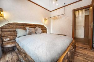 een slaapkamer met een groot bed met een houten hoofdeinde bij Host2U Authentic Bansko Apartment - Free Parking in Bansko