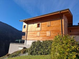 ein Holzgebäude auf einem Hügel in der Unterkunft Appt Cosy centre ville à 5 min des stations de ski in Saint-Jean-de-Sixt