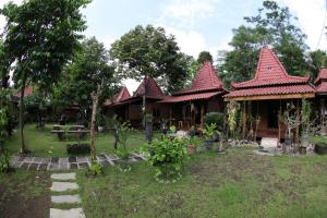 a group of houses with red roofs in a yard at Omah Garengpoeng Guest House in Borobudur