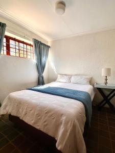 a bedroom with a large bed with a blue blanket at Katima Mountain View Lodge in Hartbeespoort