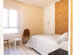 a bedroom with a white bed and a chair at Apartamento Los Castillos 2I in Tordesillas