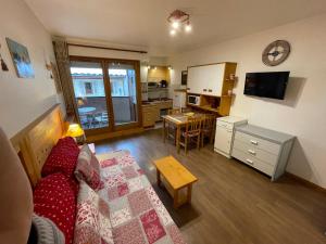 a living room with a couch and a table and a kitchen at Studio Acacia Brides Les Bains in Brides-les-Bains