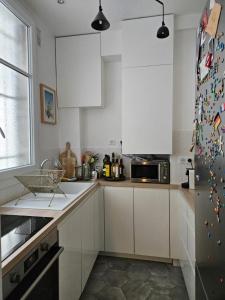 a kitchen with white cabinets and a stainless steel refrigerator at Cosy private room in Shared appartment - 1 person only ! in Paris