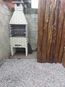 an outdoor oven sitting next to a wooden fence at Casa da Paz -Praia do Rosa in Imbituba