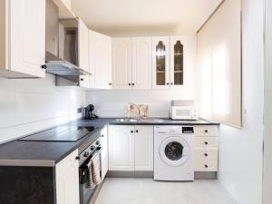 a kitchen with white cabinets and a washer and dryer at Apartamento Los Castillos 2D in Tordesillas