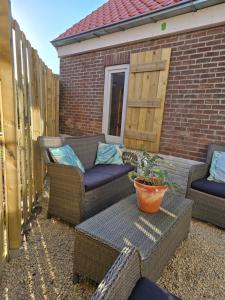 a patio with two wicker chairs and a table at Huma2025 in Eede