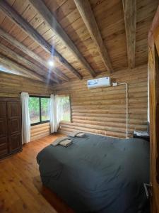 Un dormitorio con una cama en una habitación con paredes de madera. en Refugio Alpino, en La Cumbrecita 15 fotos más