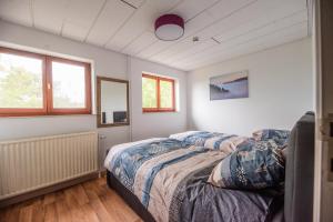 a bedroom with a bed and two windows at Cycl'eau, au coeur de l 'Ardenne in Aywaille