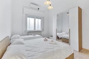 ein weißes Schlafzimmer mit zwei Betten und einem Spiegel in der Unterkunft La Corte alle Porte di Milano in Paderno Dugnano