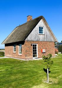 an old brick house with a roof on a grass field at Haus Treibsel in Dagebüll