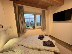 a bedroom with a bed and a window and a television at Haus Treibsel in Dagebüll