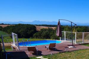 a swimming pool with two chairs and an umbrella at Gites PassionPastel in Pech-Luna
