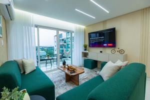 a living room with a green couch and a tv at Modern 3BR! 9fl, King Bed! Sti!, in Santiago de los Caballeros