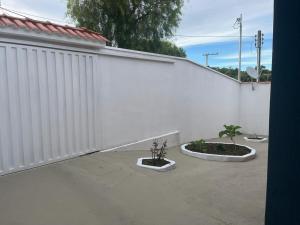 a white fence with two potted plants next to it at Casa 3 Quartos 3 vagas de Garagem in Poços de Caldas