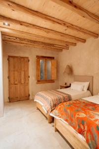 two beds in a room with wooden ceilings at Posada Rebaños in San Rafael