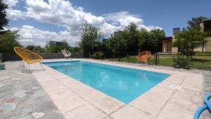 a swimming pool with two chairs and a swimming pool at Cabañas OliBer in Potrero de los Funes