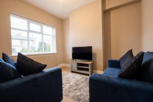 Una sala de estar con dos sofás azules y un televisor. en Cosy Home 2 Bedroom House Birkdale, en Southport