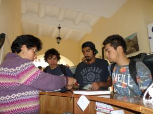 a woman is handing something to a group of people at OkiDoki Cusco Hostal in Cusco