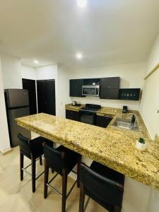 - une cuisine avec un plan de travail en granit et des appareils noirs dans l'établissement Peregrina 2 bdr In Heart of Playa, à Playa del Carmen 1 autre photo