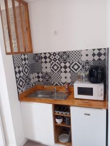 eine kleine Küche mit Spüle und Mikrowelle in der Unterkunft La petite cabane in Villebarou