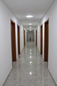 an empty corridor of a building with wooden doors at Hotel Flamboyant in Itaquaquecetuba