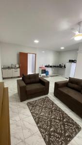sala de estar con 2 sofás marrones y cocina en Duplex Praia do Bosque, en Guriri