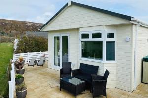 un capanno con divano e sedie su un patio di The Warren O7 ad Abersoch