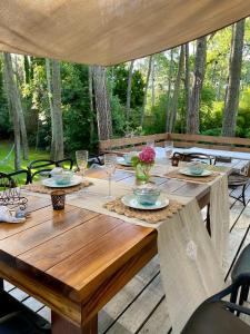 a wooden table with plates and glasses on a deck at Espectacular casa en Cariló frte al Golf 8 personas in Carilo