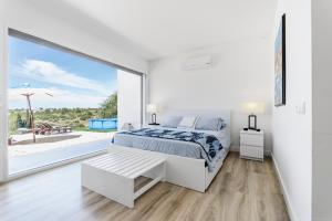 a white bedroom with a bed and a large window at Xitaka Country House - Modern Large Great Views in Torres Novas