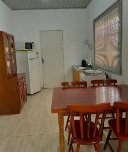 una cucina con tavolo, sedie e frigorifero di Casa cinza a São Lourenço do Sul Altre 2 foto