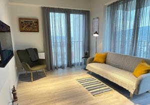 a living room with a couch and a chair at All Green Loft with Amazing Views, With 2 Balconies and AC in Tbilisi City