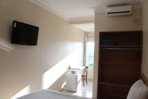 a bedroom with a bed and a tv on the wall at Hotel Flamboyant in Itaquaquecetuba