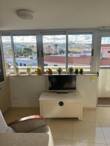 a living room with a tv and some windows at Atico acogedor con vistas in Telde